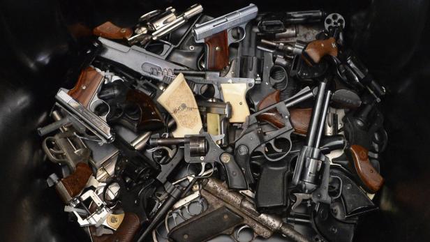 Eine Sammlung von verschiedenen Pistolen und Revolvern liegt in einem Behälter.