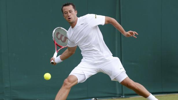 Ein Tennisspieler schlägt einen Ball vor einem grünen Hintergrund.