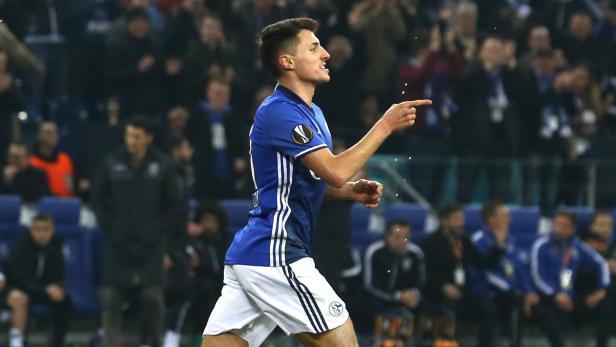 Ein Fußballspieler in blau-weißem Trikot jubelt und zeigt mit dem Finger.
