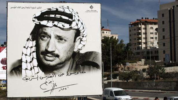 Ein großes Plakat zeigt ein Porträt von Jassir Arafat mit Kufiya vor einem Stadtbild.