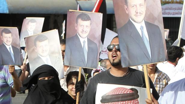 Menschen demonstrieren mit Porträts von König Abdullah II. von Jordanien.