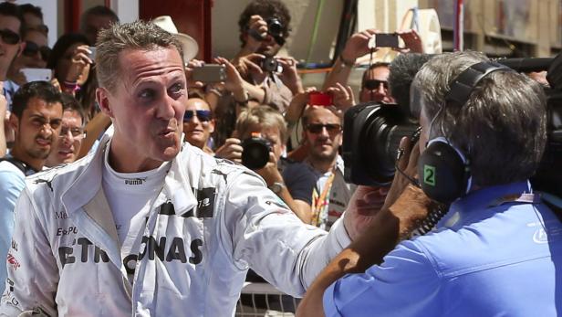 Michael Schumacher wird von einer Gruppe von Reportern und Fotografen umringt.