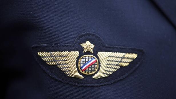 Nahaufnahme eines goldenen Pilotenabzeichens auf einer dunkelblauen Uniform.