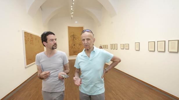 Zwei Männer betrachten Kunstwerke in einer Galerie.