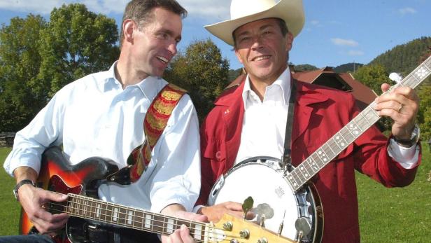 Zwei Männer spielen Gitarre und Banjo im Freien.