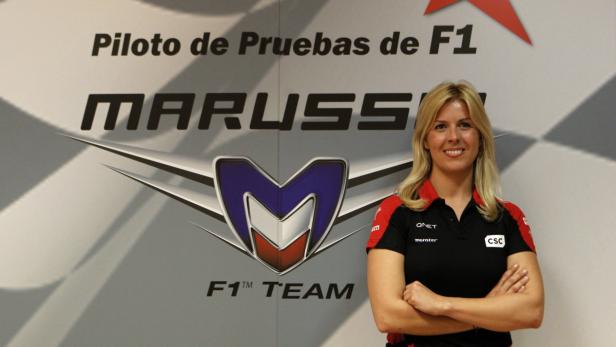 Eine Frau steht vor einem Marussia F1 Team Logo.