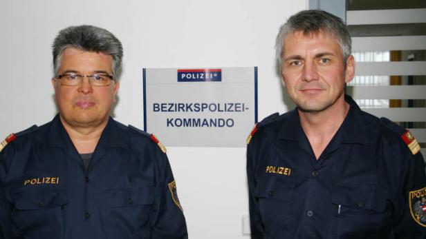Zwei Polizisten stehen vor einem Schild des Bezirkspolizeikommandos.