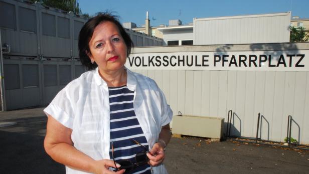 Eine Frau steht vor der Volksschule Pfarrplatz und hält eine Sonnenbrille in der Hand.