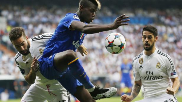 Ein Fußballspieler von Juventus Turin spielt den Ball, während zwei Spieler von Real Madrid zusehen.
