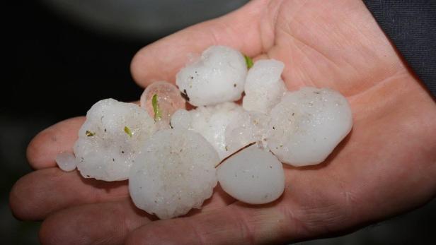 Eine Hand hält eine Ansammlung von Hagelkörnern.