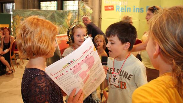 Kinder nehmen an einem Quiz mit Mikrofonen und Fragebögen teil.