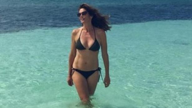 Eine Frau im Bikini steht im türkisfarbenen Wasser.