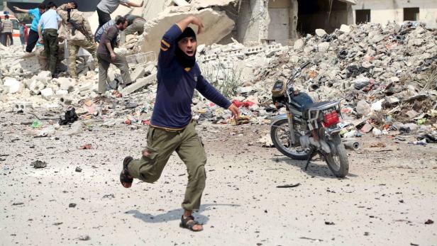 Ein Mann rennt vor Trümmern und einem zerstörten Gebäude davon.