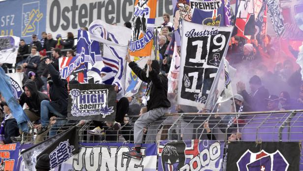 Fußballfans mit Fahnen und Bannern im Stadion, darunter „High Society“ und „Austria Wien“.