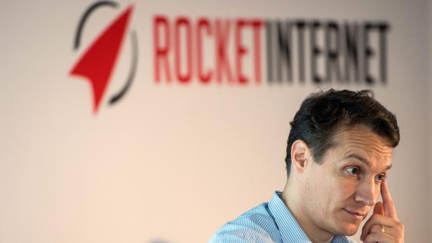 Ein Mann vor dem Rocket Internet Logo berührt seine Schläfe.