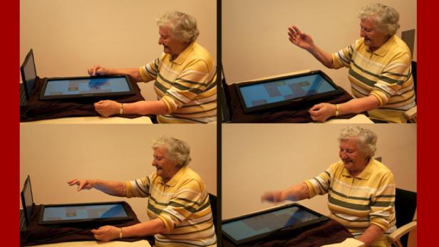 Eine ältere Frau interagiert mit einem Touchscreen-Computer.