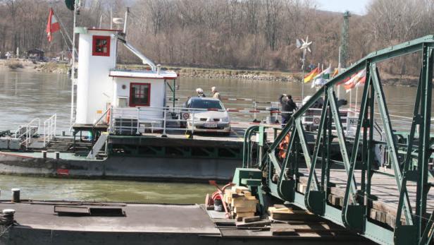 Eine Autofähre überquert einen Fluss mit einem Auto an Bord.