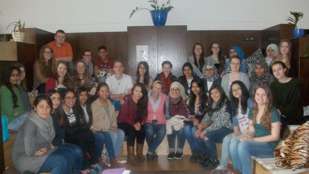 Eine große Gruppe junger Menschen sitzt und steht für ein Gruppenfoto.