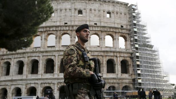 Ein Soldat in Uniform steht vor dem Kolosseum in Rom.