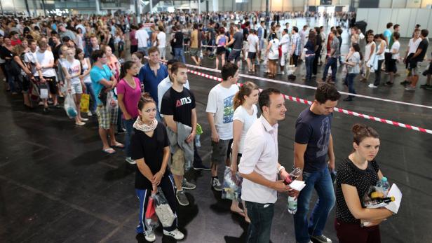 Eine lange Schlange von Menschen wartet in einer großen Halle.