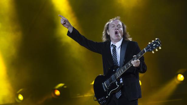 Angus Young von AC/DC spielt Gitarre und zeigt mit dem Finger ins Publikum.