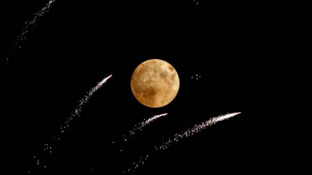 Ein Vollmond leuchtet am Nachthimmel, umgeben von Sternschnuppen.