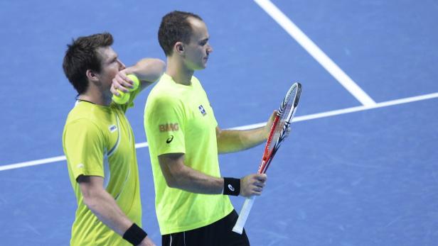 Zwei Tennisspieler in gelben Trikots auf einem blauen Platz.