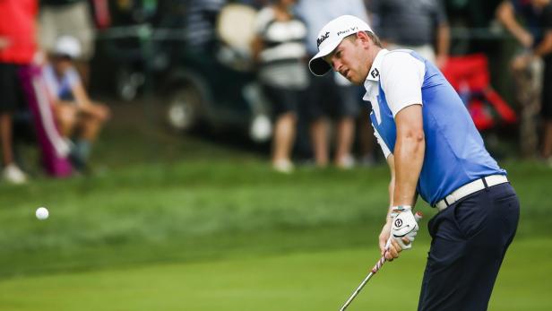 Ein Golfspieler schlägt einen Ball auf einem grünen Rasen.