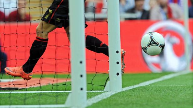 Ein Fußballspieler schießt den Ball ins Tor.