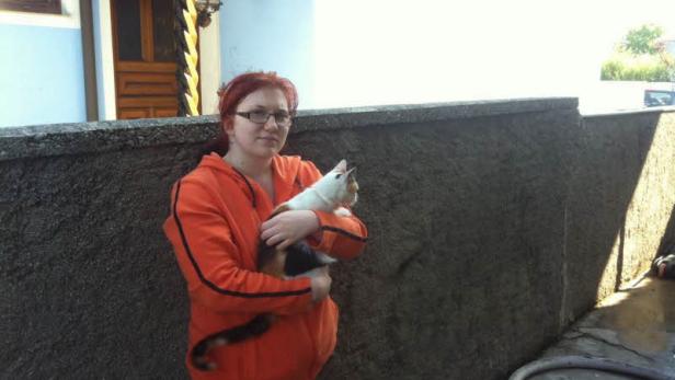 Eine Frau mit rotem Haar hält eine Katze im Arm.