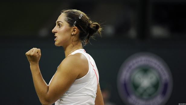 Eine Tennisspielerin ballt die Faust vor dem Wimbledon-Logo.