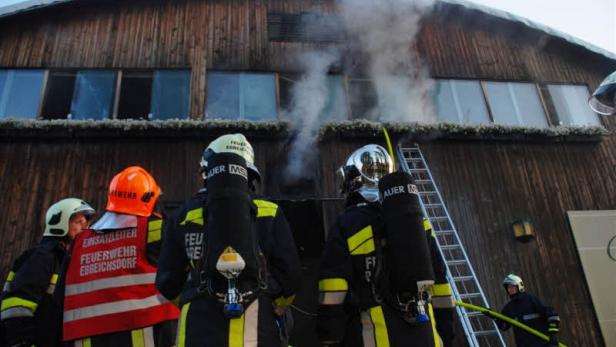 Feuerwehrleute bekämpfen einen Brand in einem Holzgebäude.