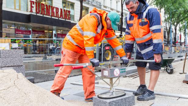 Bauarbeiter verlegen in der Wiener Mariahilferstraße Granitsteine aus Schrems.