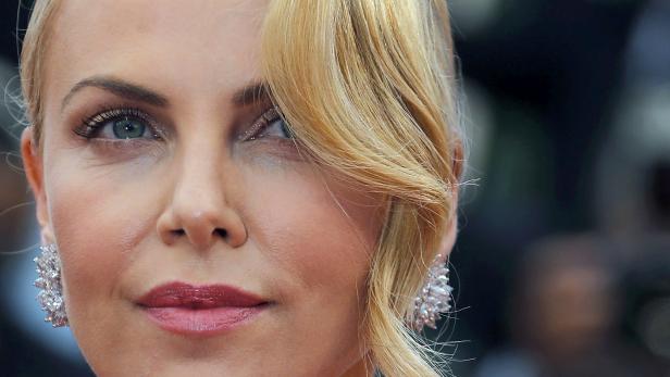Nahaufnahme von Charlize Theron mit blonden Haaren und auffälligen Ohrringen.