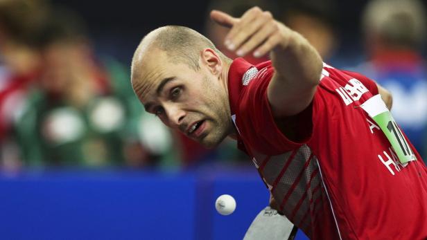 Ein Tischtennisspieler in rotem Trikot schlägt den Ball.