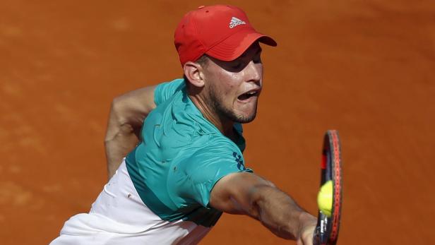 Ein Tennisspieler mit roter Kappe schlägt einen Ball auf einem Sandplatz.