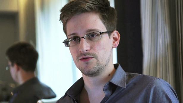 Ein Porträt von Edward Snowden mit Brille und grauem Hemd.