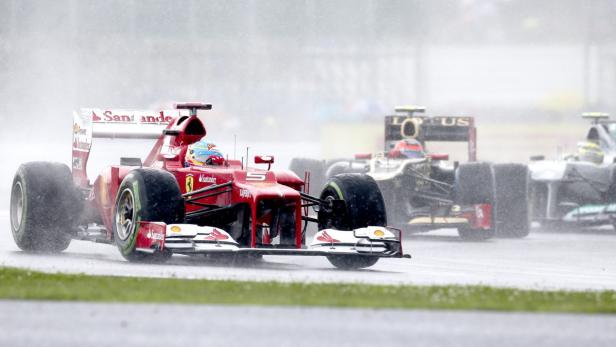Ein roter Formel-1-Rennwagen fährt im Regen.