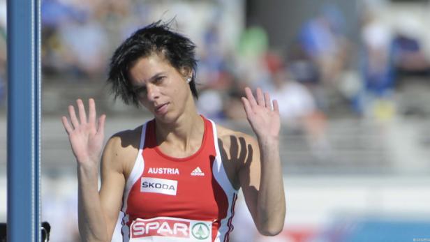 Eine österreichische Athletin winkt mit erhobenen Händen.