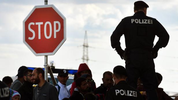 Polizisten stehen vor einer Gruppe von Menschen an einem Stoppschild.