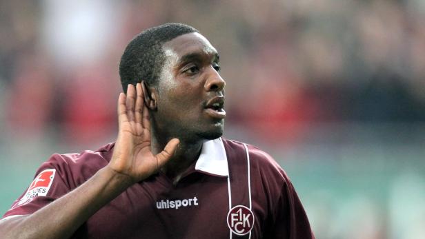 Ein Fußballspieler hält seine Hand ans Ohr, um die Fans besser zu hören.