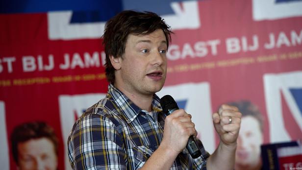 Jamie Oliver spricht bei einer Veranstaltung in Hemer vor einem Hintergrund mit Union-Jack-Motiven.
