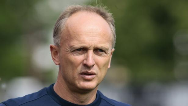 Ein Mann mit kurzen, hellbraunen Haaren und einem blauen Hemd blickt in die Ferne.