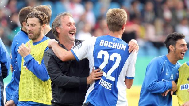 Der Trainer umarmt einen Spieler des VfL Bochum, während andere Spieler im Hintergrund jubeln.