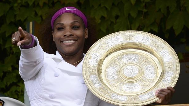 Serena Williams lächelt und hält die Wimbledon-Trophäe.