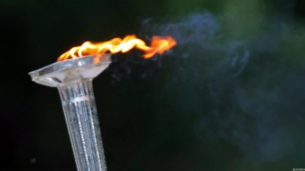 Eine Fackel mit einer hellen Flamme vor einem dunklen Hintergrund.
