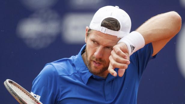 Ein Tennisspieler wischt sich den Schweiß von der Stirn.
