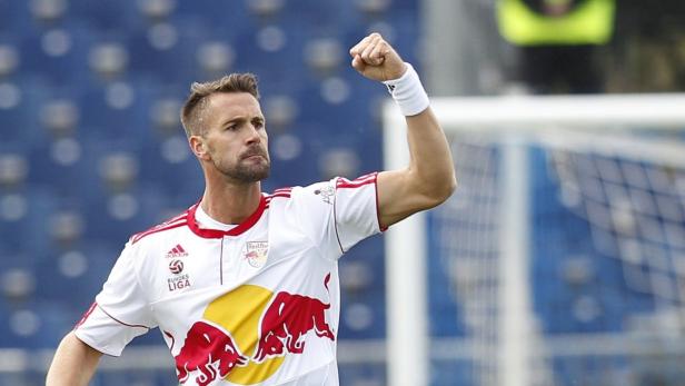 Ein Fußballspieler im Trikot von Red Bull jubelt mit erhobenem Arm.
