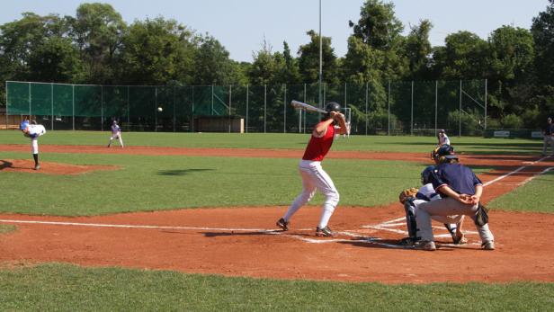 Ein Baseballspieler schlägt den Ball, während der Fänger hinter ihm kauert.