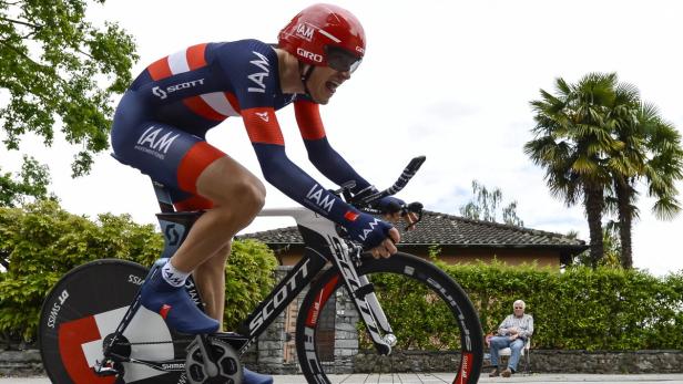 Ein Radrennfahrer in roter und blauer Sportbekleidung fährt ein Zeitfahrrad.